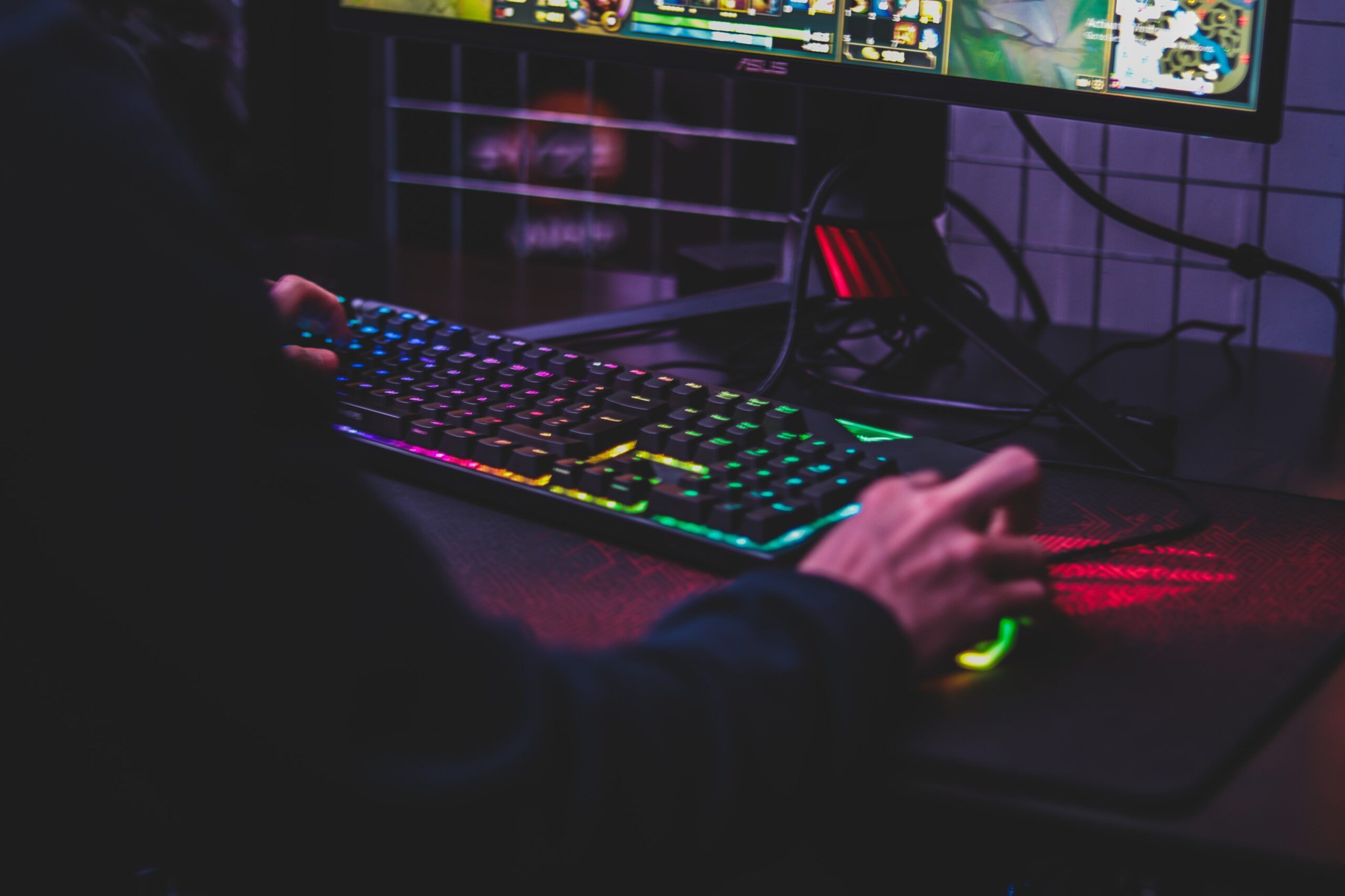Sprzęt komputerowy, przed którym siedzi gracz, na monitorze widać, że gra w grę